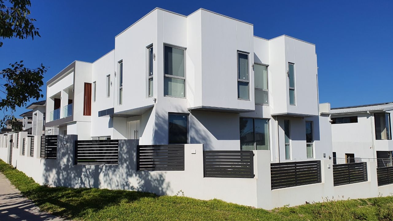 Freshly painted white townhouse development with dark slatted fence