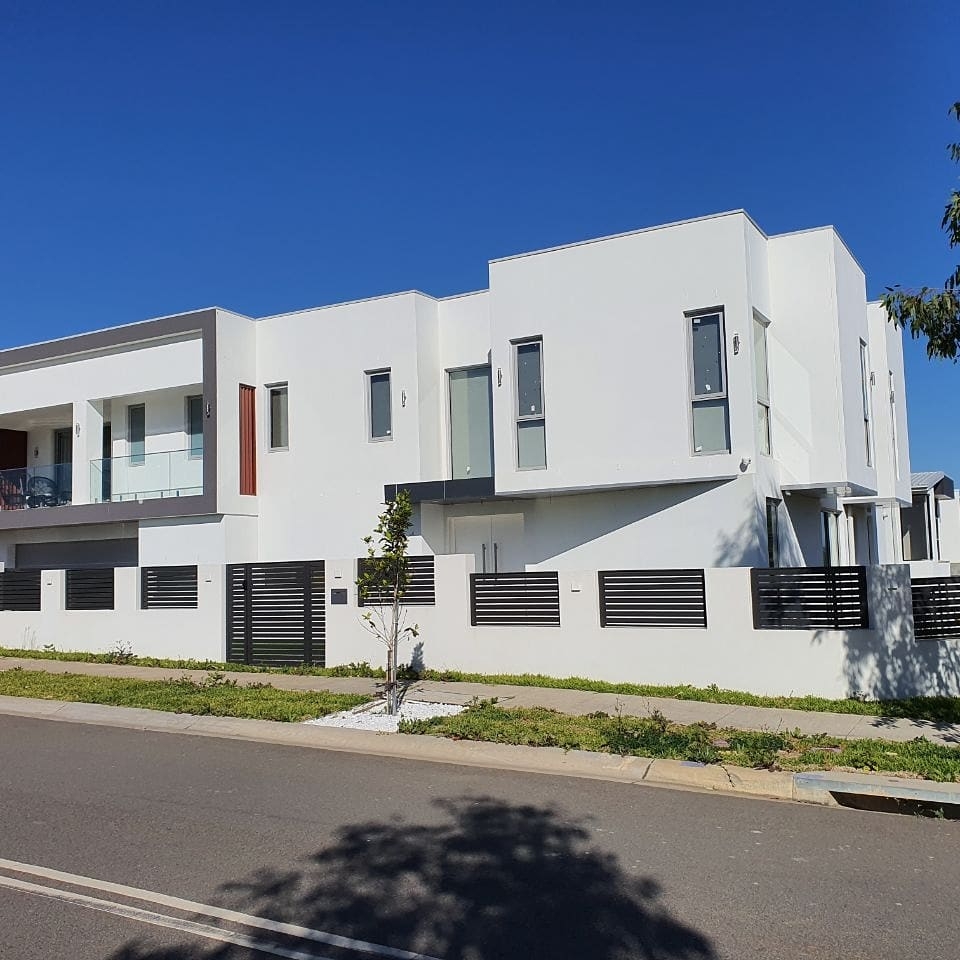 Street view of a freshly painted white townhouse development