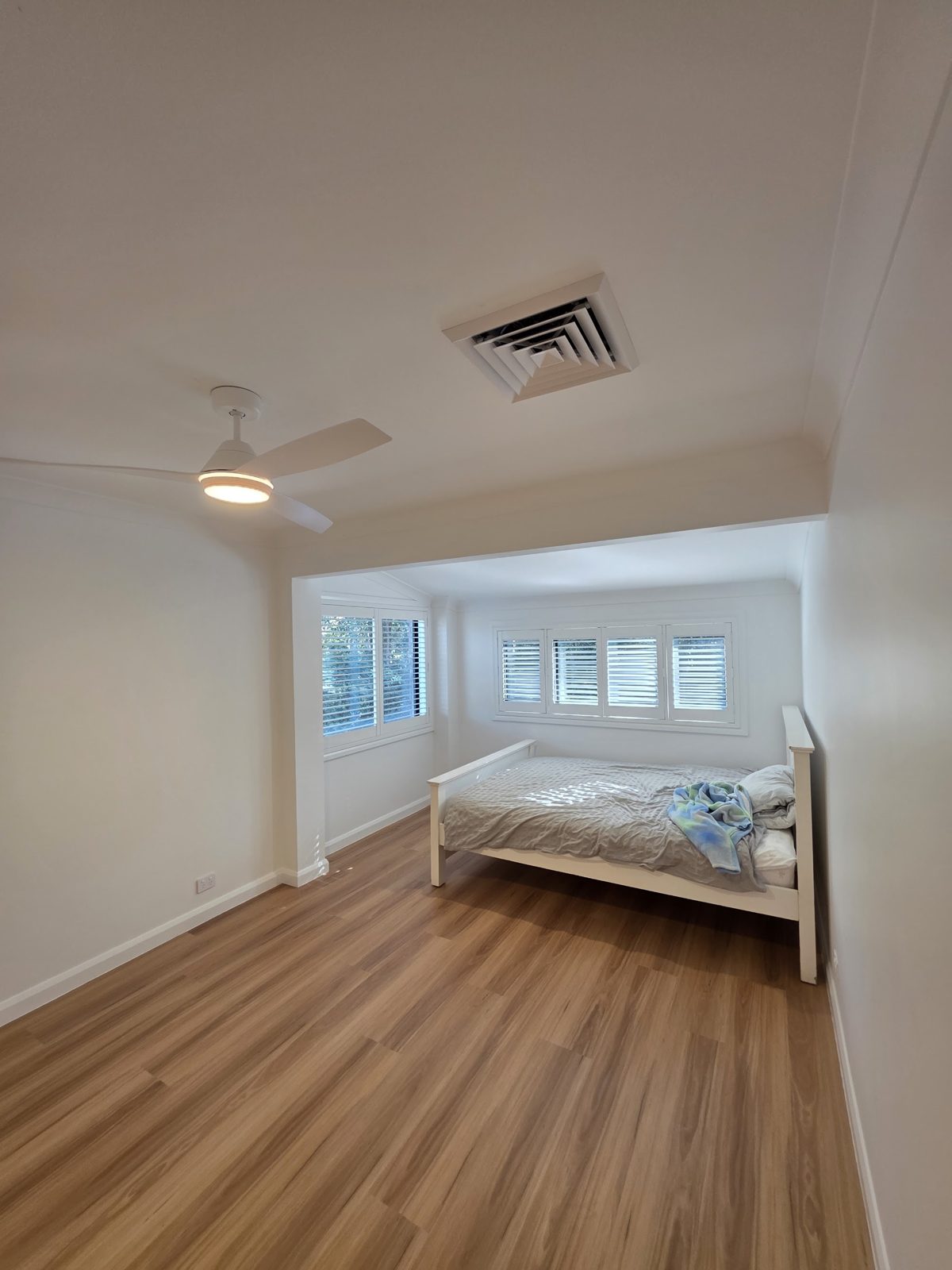Freshly painted bedroom with white plantation shutters and timber floor