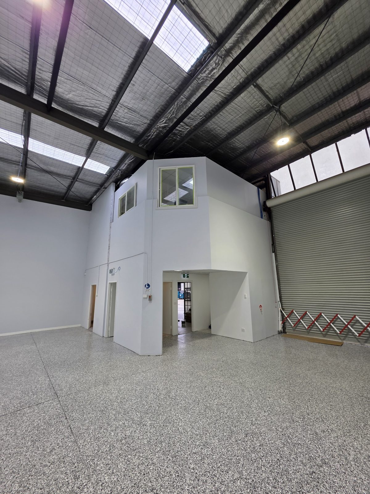Freshly painted warehouse interior with white mezzanine office and roller door